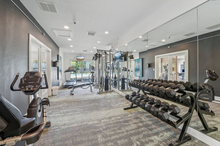 Modern fitness center with state-of-the-art gym equipment, including treadmills and dumbbells, in a bright, spacious setting.