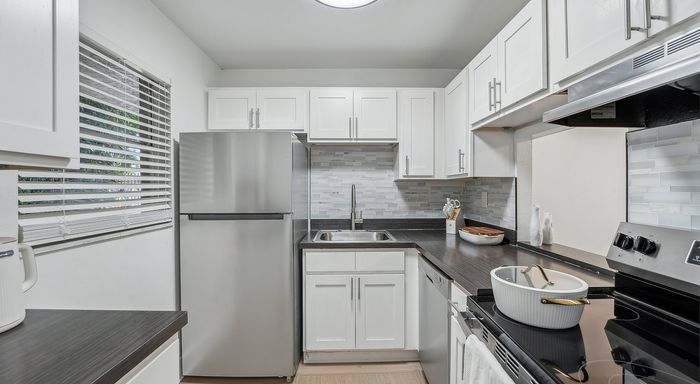 Chic modern kitchen with sleek stainless steel appliances, elegant backsplash, and pristine white cabinetry.