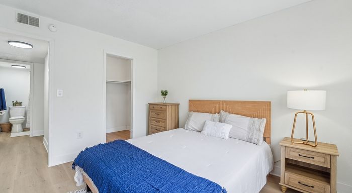 Bright and cozy bedroom with modern wooden furnishings and a tranquil atmosphere, featuring a neatly made bed, soft lighting, and convenient bathroom access.