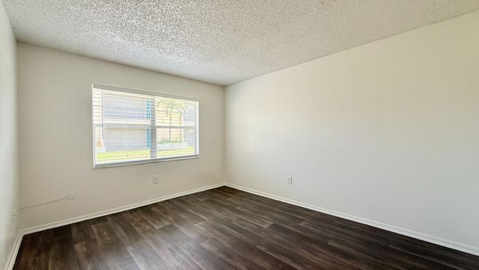 a bedroom with large window and dark vinyl floor