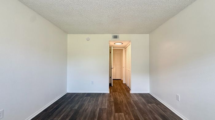 Bright, minimalist room with elegant wood flooring and ample natural light, featuring a white door leading to additional space.