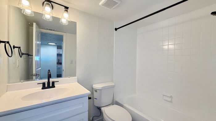 Modern bathroom featuring sleek vanity, elegant lighting, and a pristine bathtub with stylish black fixtures.