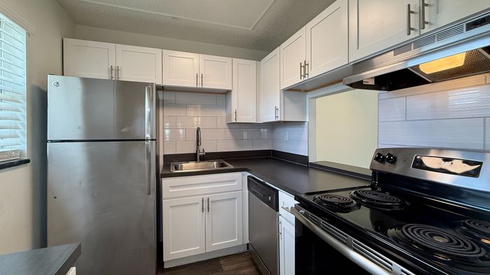 Modern kitchen with sleek stainless steel appliances, white cabinetry, and elegant dark countertops offering a stylish and functional space.