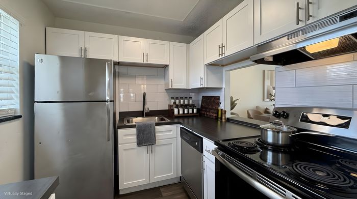 Sleek modern kitchen with stainless steel appliances, elegant white cabinetry, and stylish dark countertops, perfect for culinary enthusiasts.