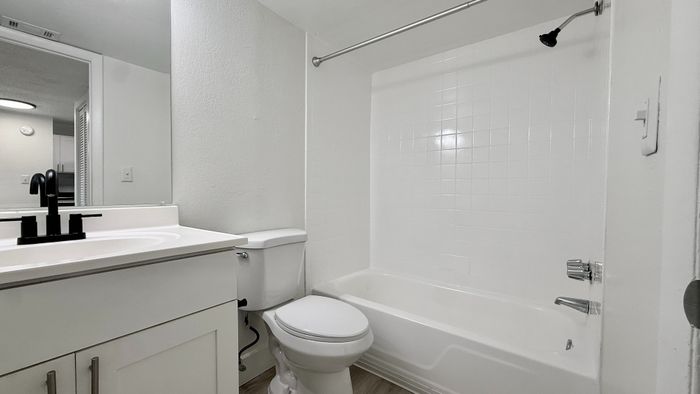 Contemporary bathroom with sleek vanity, elegant fixtures, and a pristine tiled bathtub.