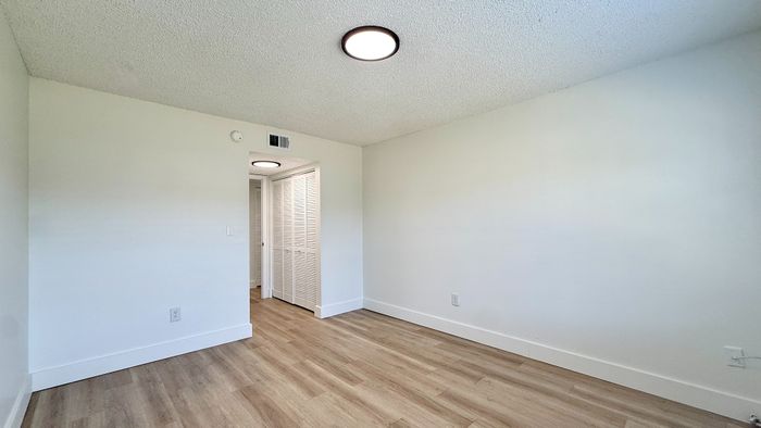 Bright and spacious room with elegant wooden flooring, featuring a large closet and modern ceiling lights.