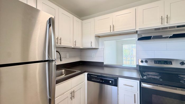 Modern kitchen with sleek stainless steel appliances, elegant white cabinetry, and a convenient pass-through window.