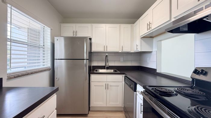 Modern kitchen with sleek stainless steel appliances, elegant white cabinetry, and expansive countertop space.