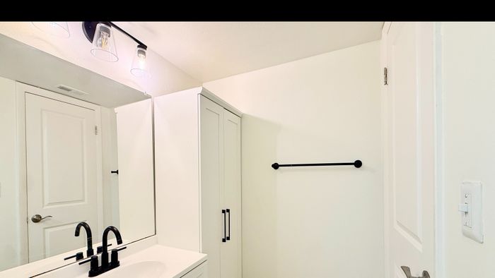 Elegant bathroom featuring sleek black fixtures, a modern sink, and ample storage in a bright, minimalist design.