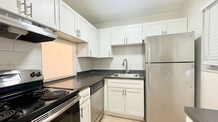 Modern kitchen with sleek stainless steel appliances, elegant white cabinetry, and a stylish black countertop.