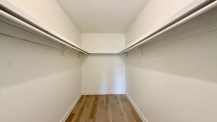 Spacious walk-in closet with dual hanging rails and elegant wooden flooring, perfect for organized living.