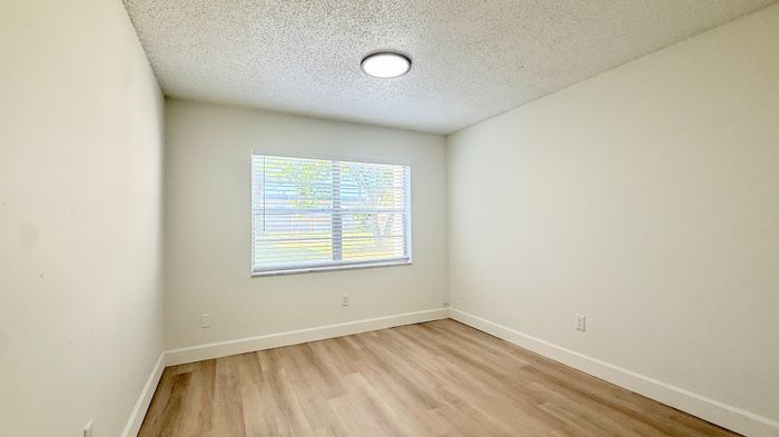 Bright and airy bedroom with large window and elegant wood flooring, perfect for modern living.