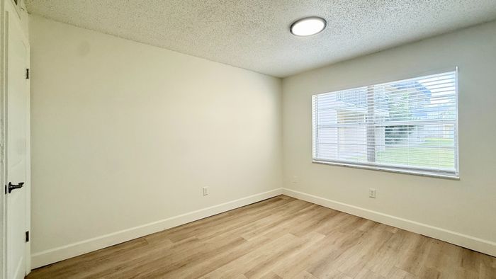 Bright and airy bedroom with large window and modern wooden flooring, perfect for cozy living.