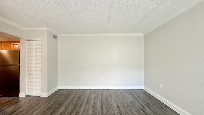 Bright and airy living space with sleek wooden floors, neutral walls, and modern stainless-steel appliances in an open-plan layout.