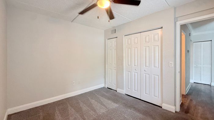 Bright and spacious bedroom with fresh carpet, ceiling fan, and ample closet space.