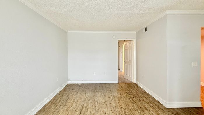 Bright and inviting room with sleek wood flooring and soft neutral walls, ready to be transformed into your ideal living space.