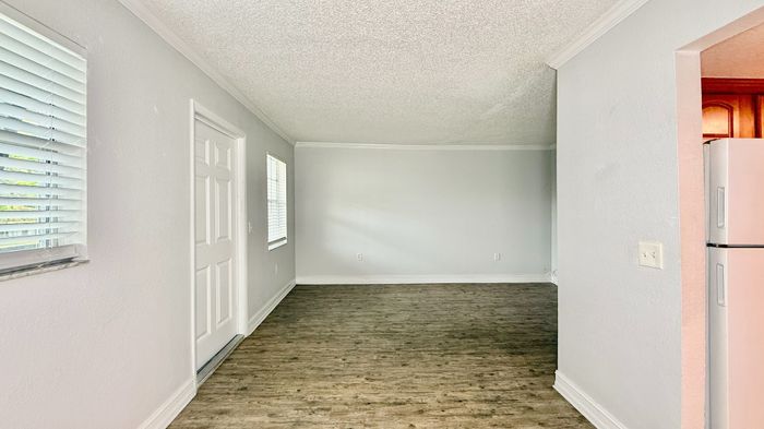 Bright and inviting empty room with large windows and stylish wooden flooring, perfect for creating your dream living area.