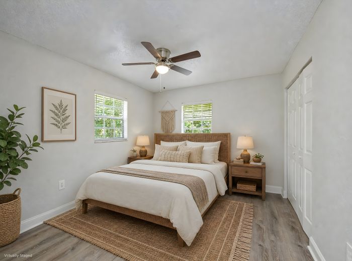 Bright and inviting bedroom with elegant neutral tones, featuring a cozy bed, stylish decor, and abundant natural light from two large windows.