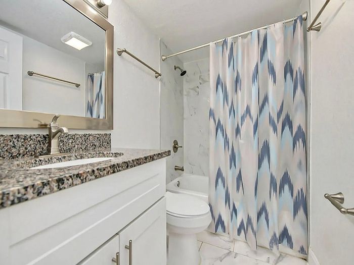 Modern bathroom featuring elegant granite countertops, sleek fixtures, and stylish patterned shower curtain.