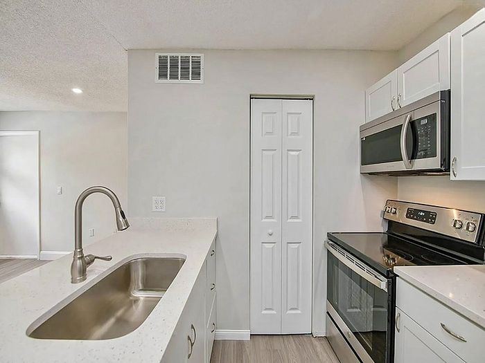 Modern kitchen with sleek stainless steel appliances, elegant white cabinetry, and a stylish quartz countertop island.