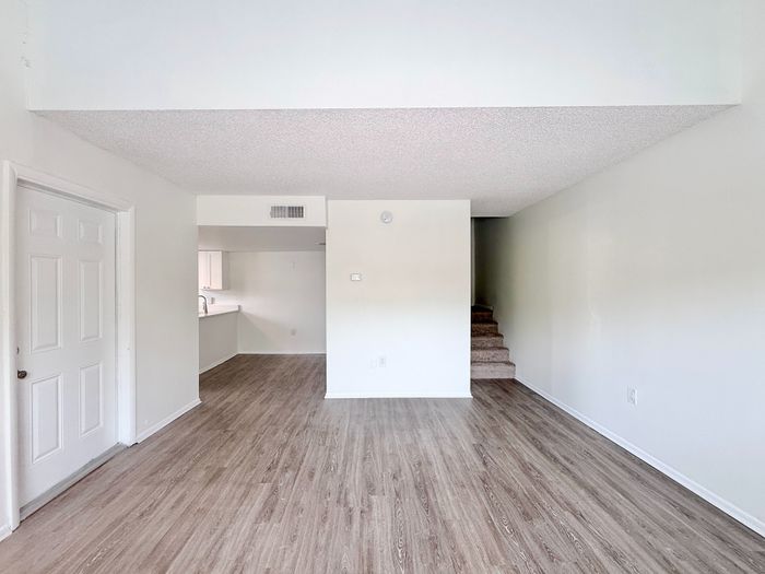 Bright and spacious interior featuring modern laminate flooring, open-concept layout, and a cozy staircase leading to an upper level.