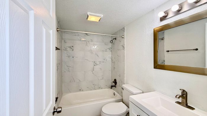 Elegant bathroom with marble-tiled shower, modern vanity, and stylish mirror lighting.