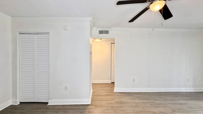Bright and inviting living space with elegant wood flooring and modern ceiling fan, perfect for a stylish home atmosphere.