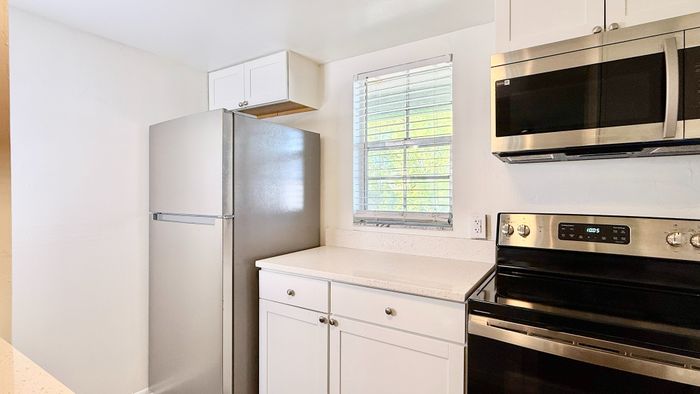 Modern kitchen with sleek stainless steel appliances, gleaming white cabinets, and ample countertop space.
