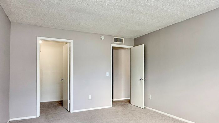 Spacious bedroom with fresh, neutral paint and plush carpet, inviting natural light for a cozy ambiance.