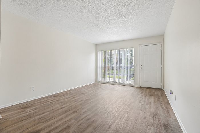 Bright and inviting living room with elegant hardwood floors, large window allowing natural light, and modern minimalist design.