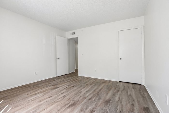 Bright and spacious bedroom featuring elegant wood flooring and fresh white walls, perfect for a modern touch.