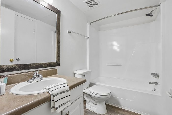 Modern bathroom with a sleek design featuring a large mirror, stylish sink, and immaculate bathtub with a curved shower rod.
