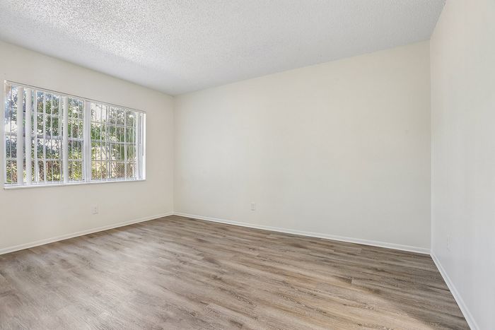 Bright, open room with elegant hardwood flooring and large window offering natural light.