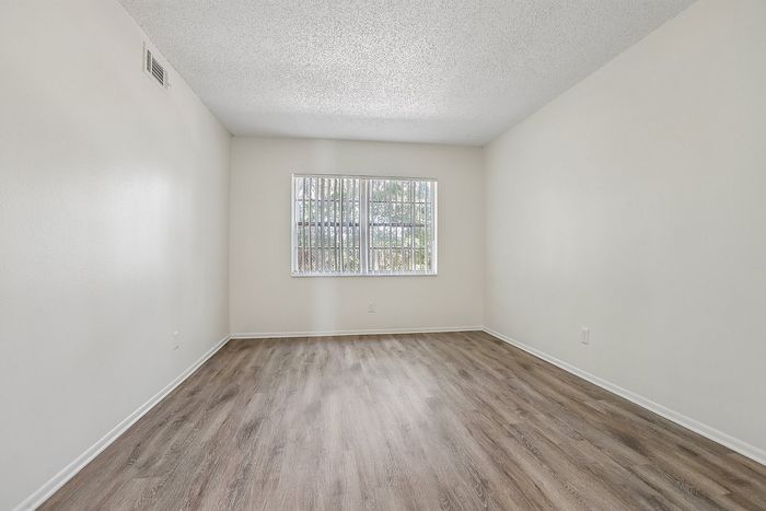 Bright and inviting room with elegant wood flooring and large window, perfect for a cozy living space.