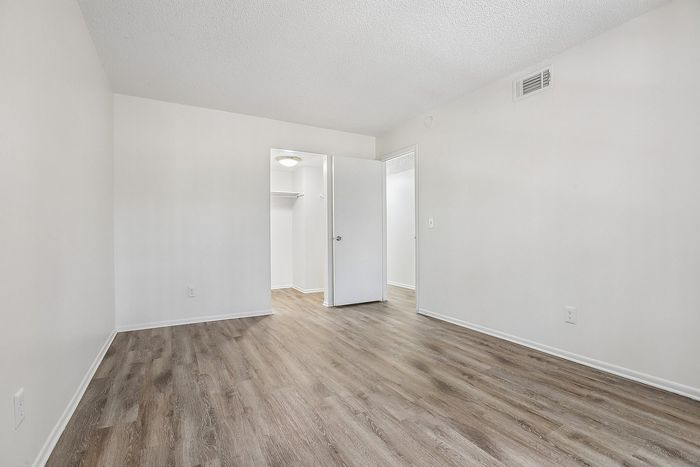 Modern and inviting bedroom with elegant wood flooring and a spacious walk-in closet.
