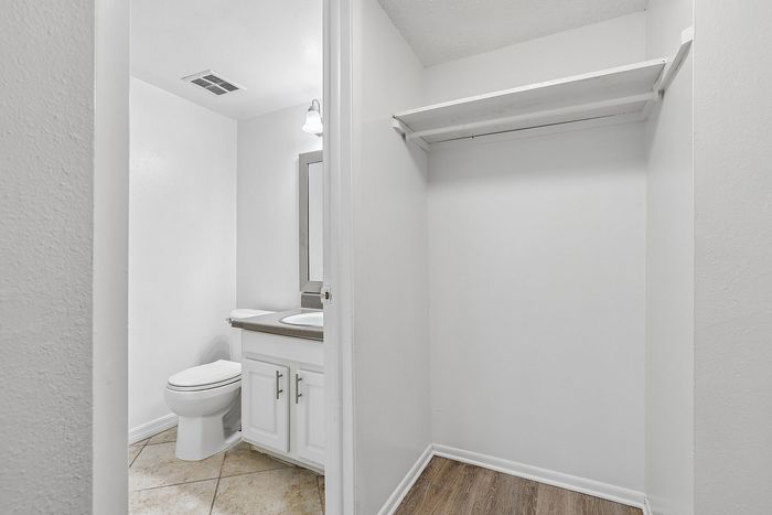Bright, modern bathroom with sleek fixtures and adjacent spacious walk-in closet, featuring clean lines and ample storage space.