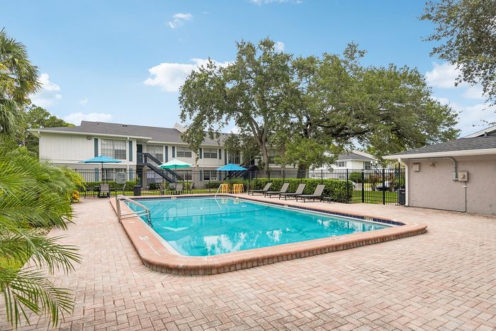 Inviting apartment complex with a pristine swimming pool surrounded by lush greenery, perfect for relaxation and leisure.