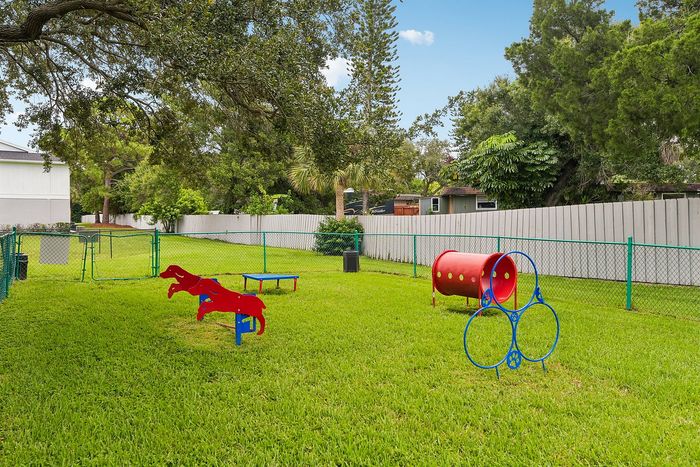 Charming dog park with agility equipment surrounded by lush greenery and secure fencing, perfect for pet-friendly communities.