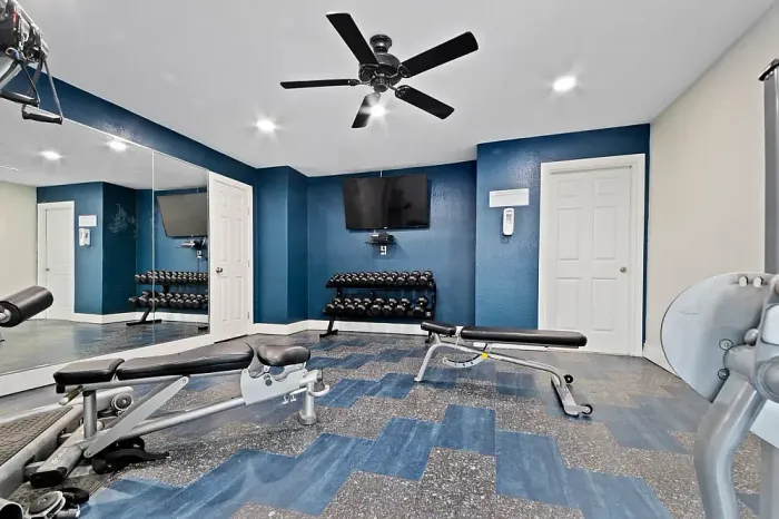 Modern fitness center with state-of-the-art gym equipment, including treadmills and exercise bikes, set against stylish blue and white decor.