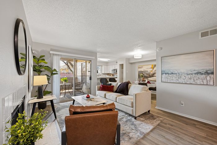 Inviting living room with cozy seating, a modern kitchen, and natural light from sliding doors leading to a charming balcony.