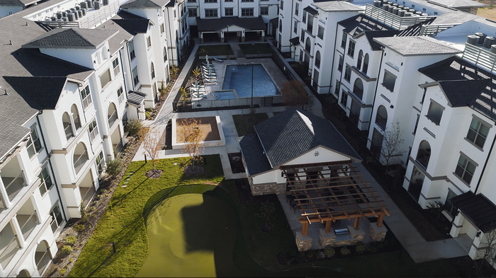 Luxurious apartment complex showcasing modern architecture, a central swimming pool, and a cozy outdoor pavilion with lush green surroundings.