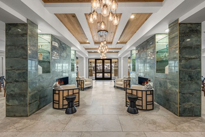 Elegant lounge area with plush seating, modern fireplaces, and artistic lighting in a luxurious apartment complex.
