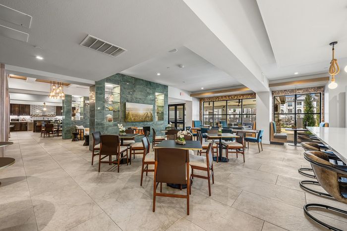 Modern communal dining area with elegant seating, large windows, and contemporary lighting, perfect for social gatherings.
