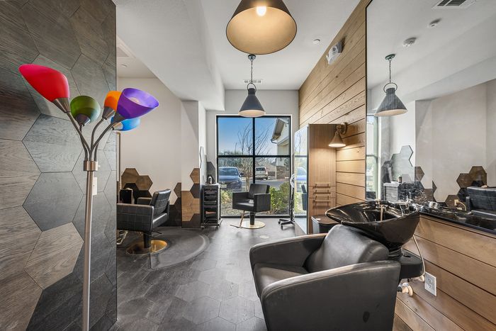 Modern salon interior with stylish hexagonal wall panels, sleek black salon chairs, and vibrant lighting fixtures creating a chic atmosphere.