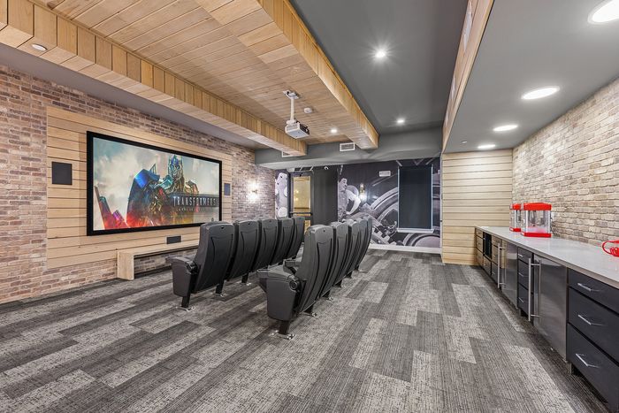 Modern home theater room featuring plush seating, a large screen, ambient lighting, and a sleek popcorn station.