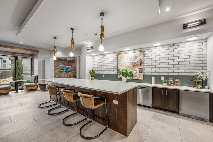 Sleek modern kitchen with a spacious island, industrial pendant lights, and cozy dining nook overlooking a garden view.