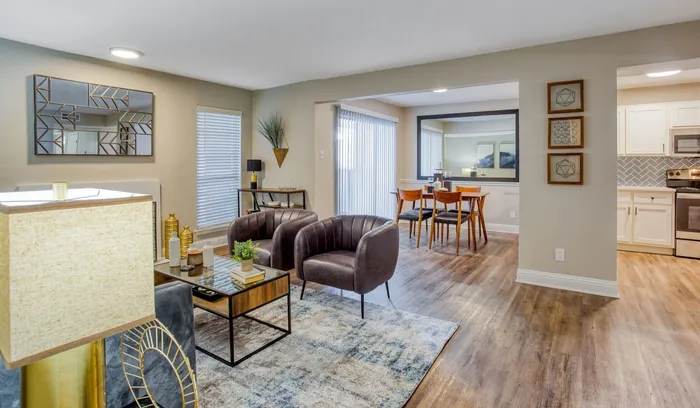 Modern open-plan living room with stylish furnishings, leading to a chic dining area and contemporary kitchen with stainless steel appliances.