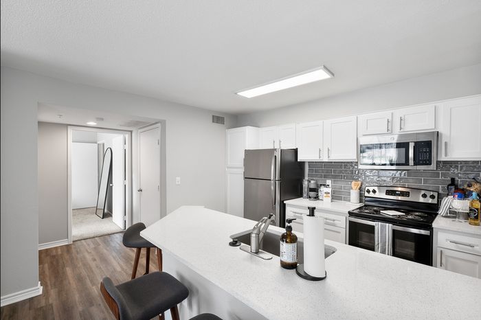Modern kitchen with sleek stainless steel appliances, white cabinetry, and a chic breakfast bar.