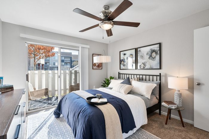 Charming bedroom with a cozy ambiance, featuring a comfortable bed, elegant decor, and natural light from sliding glass doors leading to a private patio.