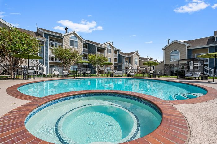 Charming apartment complex with inviting round swimming pool and lush landscaping, perfect for relaxation and outdoor enjoyment.